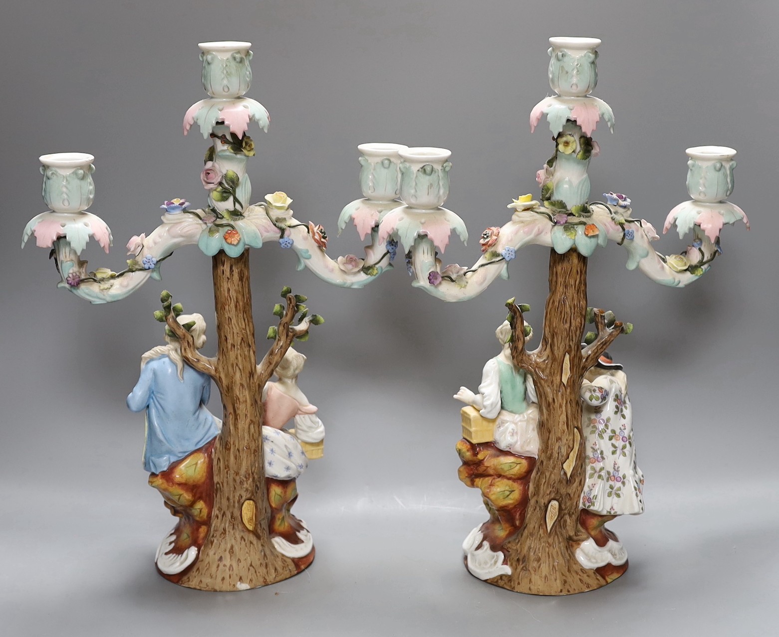 A pair of continental porcelain figural candlesticks and a similar candelabra base, together with a encrusted porcelain two handled jar with floral decoration, tallest 39cm, (4)
